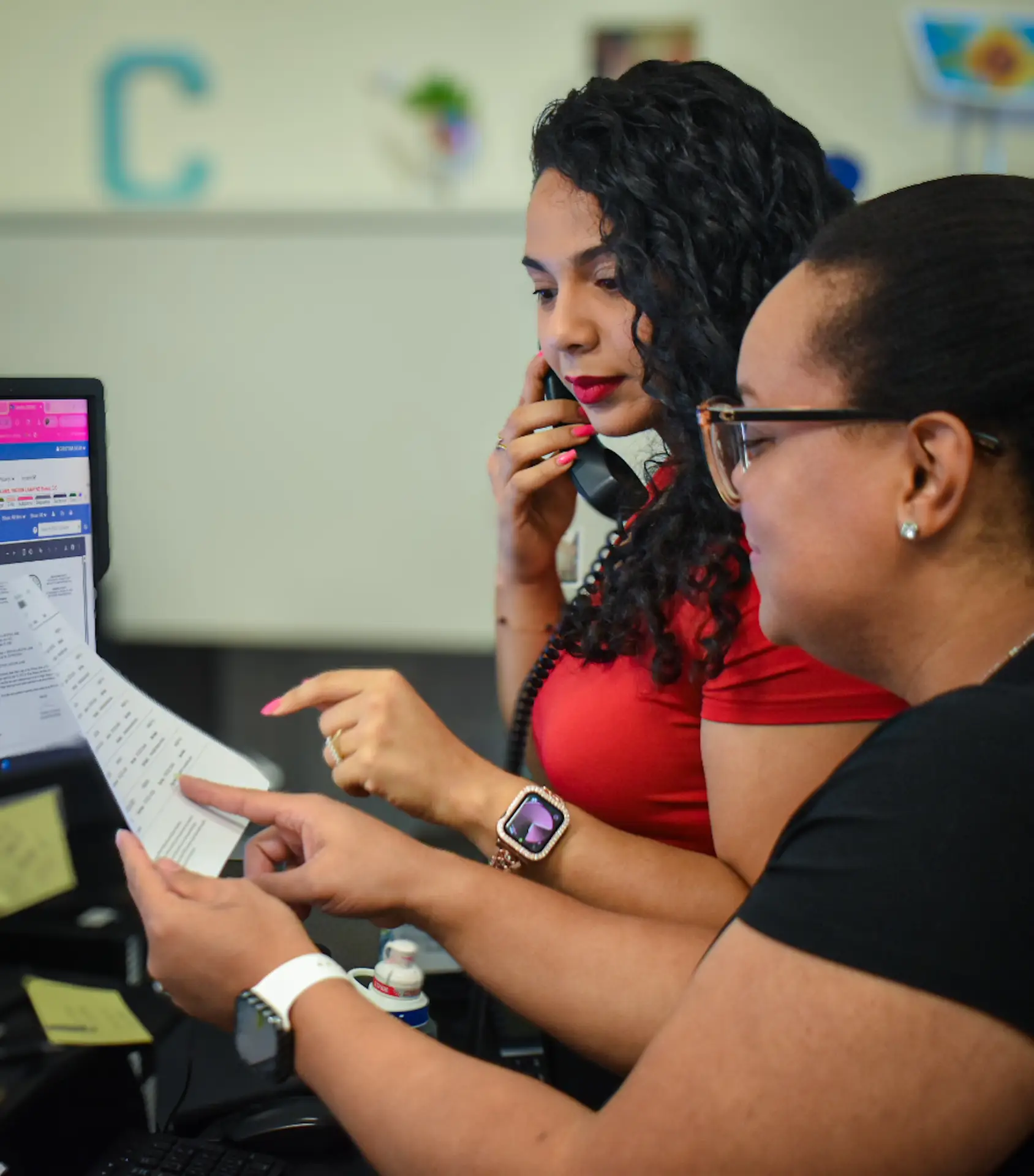 Women collaborating on phone and documents